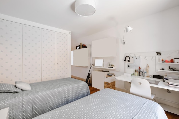 Een charmante slaapkamer met twee bedden bedekt met een grijze deken