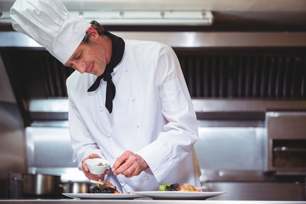 Een chef-kok die specerijen op een gerecht strooit.