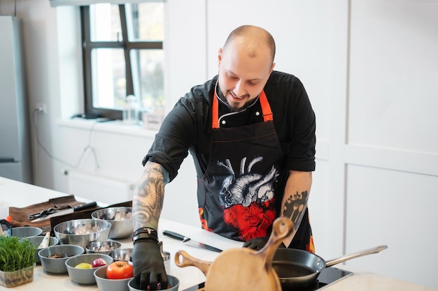 Een chef-kok met een bestektattoo staat aan de snijtafel