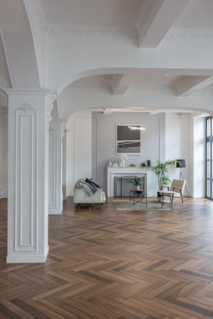 een chique duur helder interieur van een enorme woonkamer in een historisch herenhuis met gebogen bogen kolommen en witte muren versierd met ornamenten en stucwerk