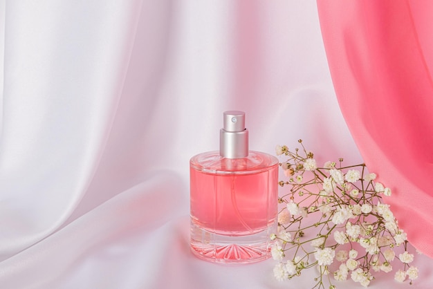 Een chique fles parfum voor vrouwen met een florale delicate geur op een witte satijn achtergrond witte bloemen Front view Product presentatie