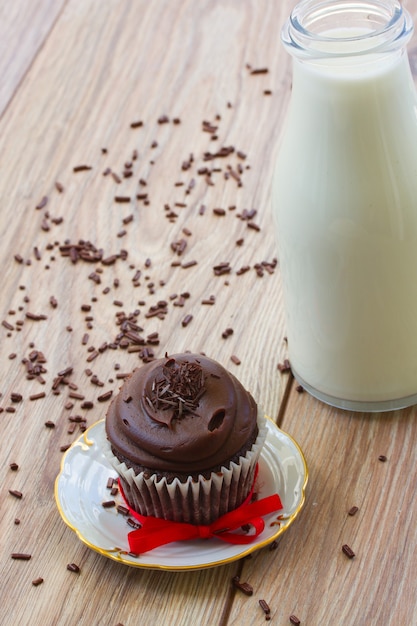 Een chocolade cupcake in plaat met melk op houten tafel