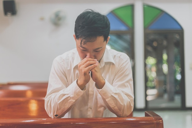 Een christelijke man zit en bidt met een nederig hart in de kerk.