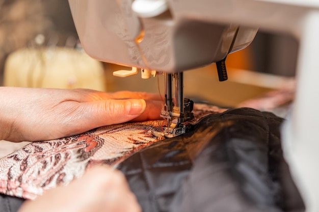 Een close-up beeld van de hand van het naaiproces van een oude vrouw met behulp van de selectieve focustechniek van de naaimachine