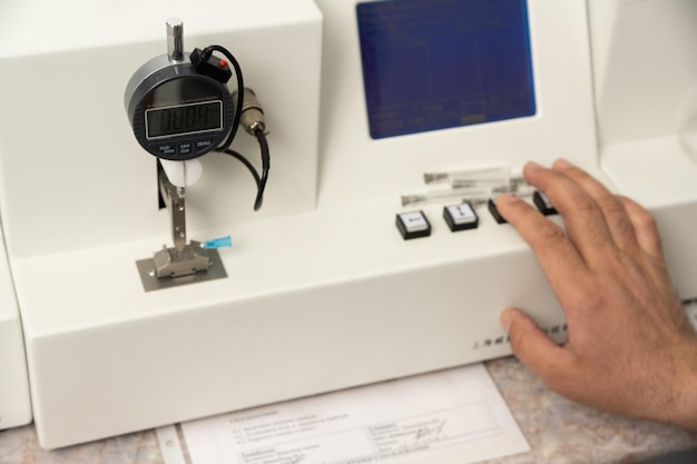 Een close-up shot van een hand die een medische machine gebruikt om farmaceutische spuiten te testen en te vervaardigen