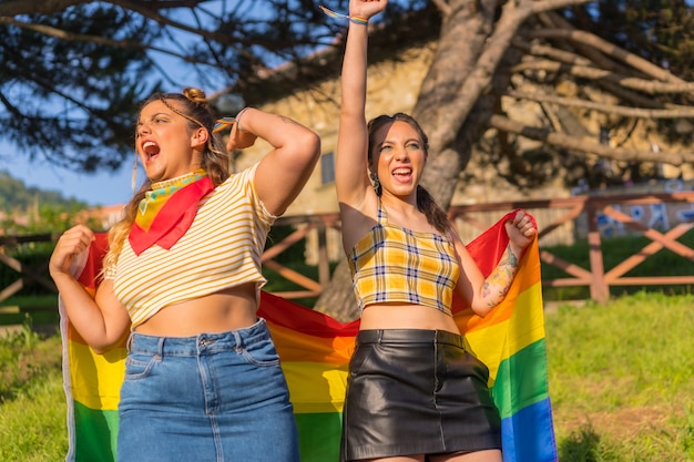 Een close-up shot van twee jonge blanke vrouwen die de LGBT-trotsvlag buiten vasthouden