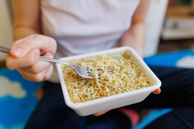 Een close-up van bovenaanzicht van handen die de consumptie van junkfood toont met instantnoedels