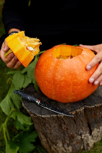 Een close-up van de hand van de mens snijdt een deksel van een pompoen terwijl hij een Jack Olantern voorbereidt. Halloween. Decoratie voor feest.