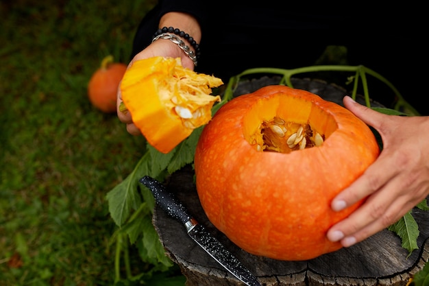 Een close-up van de hand van de mens snijdt een deksel van een pompoen terwijl hij een Jack Olantern voorbereidt. Halloween. Decoratie voor feest.