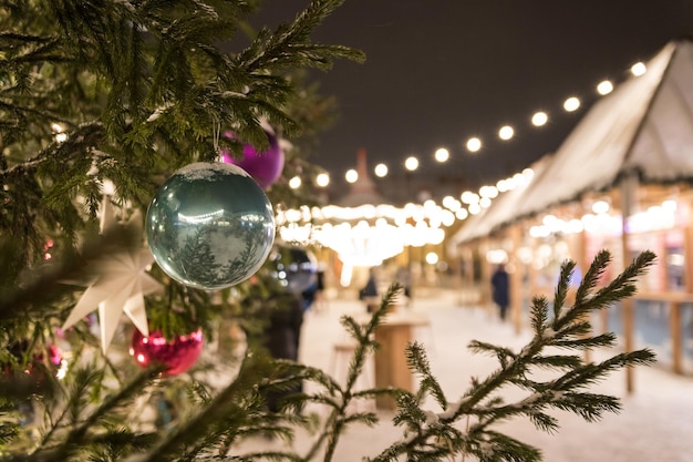 Een close-up van een feestelijk versierde buitenkerstboom met groene bal op de achtergrond van een kerstmarkt Mooie besneeuwde winterlandschappen van de kerstmarkt in Sint-Petersburg