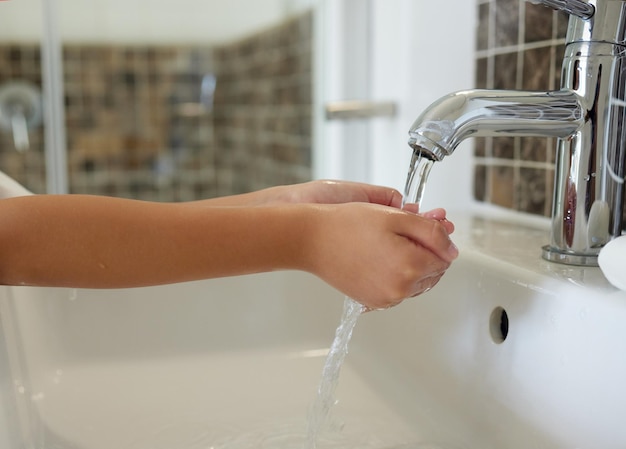 Foto een close-up van een kind dat haar handen wast bij de gootsteen in een badkamer met stromend kraanwater een kind dat hygiëne en reinheid beoefent door haar vingers schoon te maken voor viruspreventie