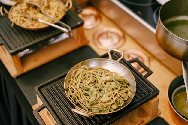 Een close-up van een koekenpan met spaghetti op een gietijzeren fornuis in de keuken tijdens het koken