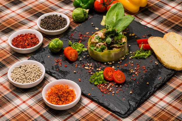 Een close-up van een serveertafel met smakelijke paddenstoelensalade met groentenbrood en kruiden op een zwart bord