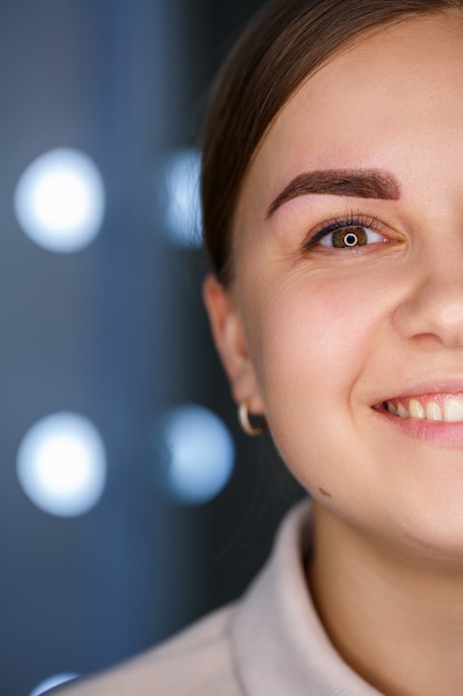 Een close-up van het gezicht van een jonge vrouw die net een permanente wenkbrauwtatoeage heeft laten zetten.