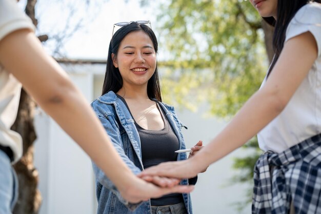 Een close-up van universiteitsstudenten die hun handen bij elkaar zetten terwijl ze in hun universiteitspark staan