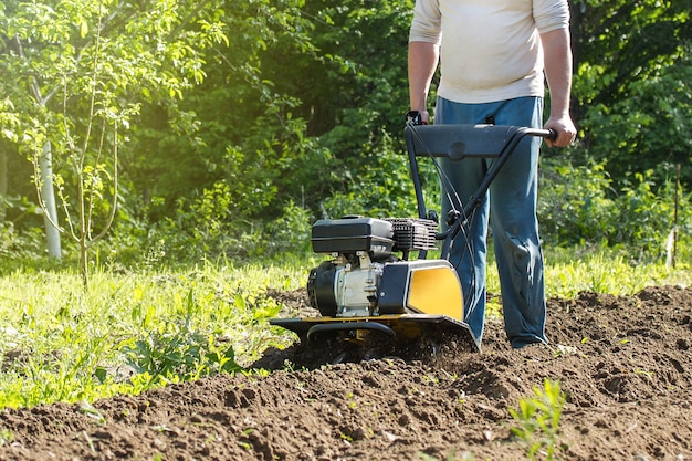 Een close-up zicht op de motorcultivator tijdens het lenteseizoen tuinwerkconcept van het ploegproces