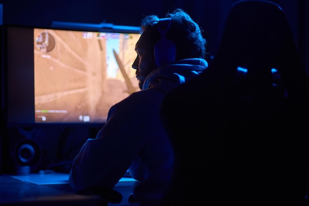 Een coder werkt's nachts laat op een computerscherm en gebruikt een smartphone-app