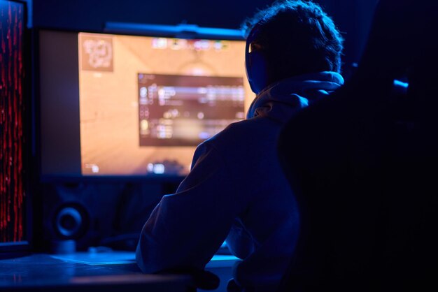 Een coder werkt's nachts laat op een computerscherm en gebruikt een smartphone-app