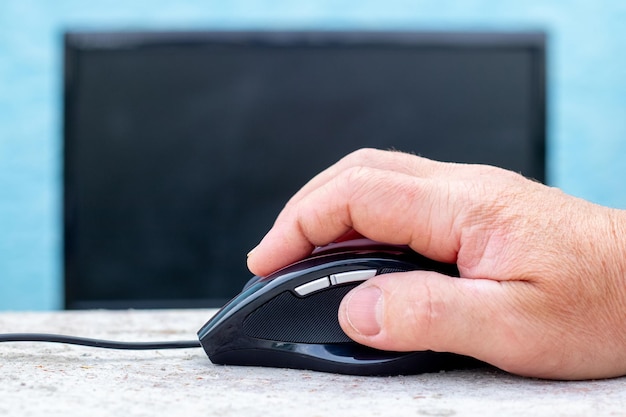 Een computermuis in de hand van een man bij een monitor