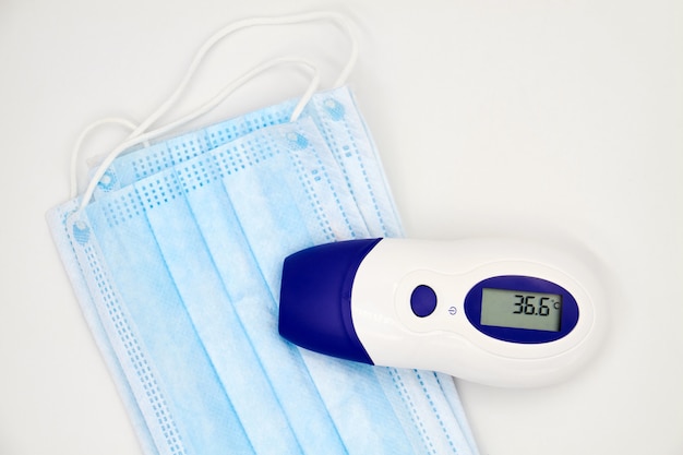 Een contactloze infraroodthermometer op de beschermende medische maskers