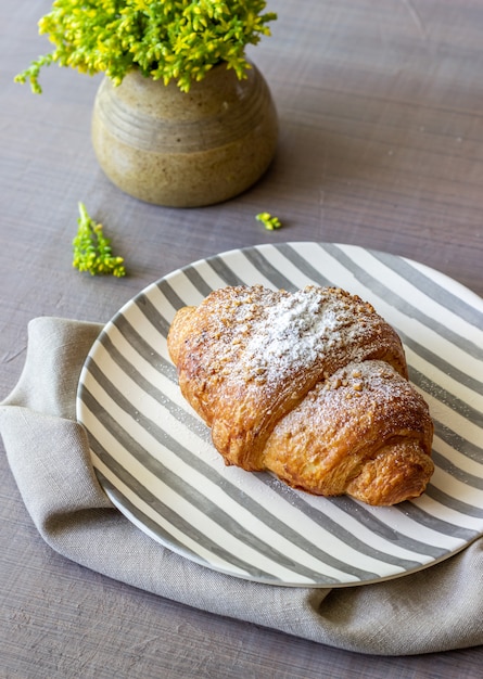 Een croissant en koffie op een grijs. De bloemen. Ontbijt.