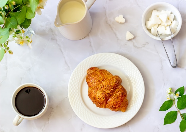 Een croissant en koffie op een marmeren oppervlak