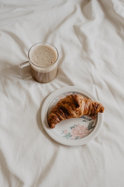 Foto een croissant met een kop koffie op een bed ernaast