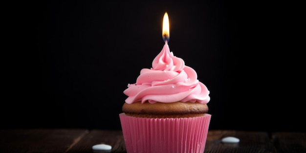 Een cupcake met roze glazuur en een brandende kaars erop