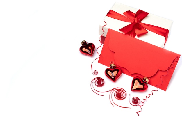 Een decoratie op een witte achtergrond voor Valentijnsdag, bestaande uit een feestelijk decor met rode enveloppen en geschenkverpakkingen versierd met een rode strik, evenals ruimte voor tekst