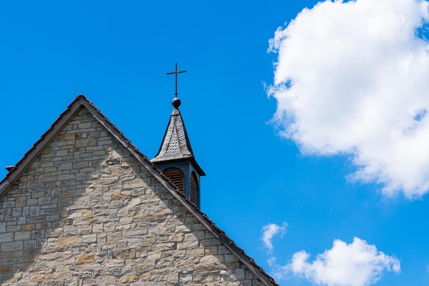 Een deel van het kerkdak met een kruis tegen een blauwe lucht