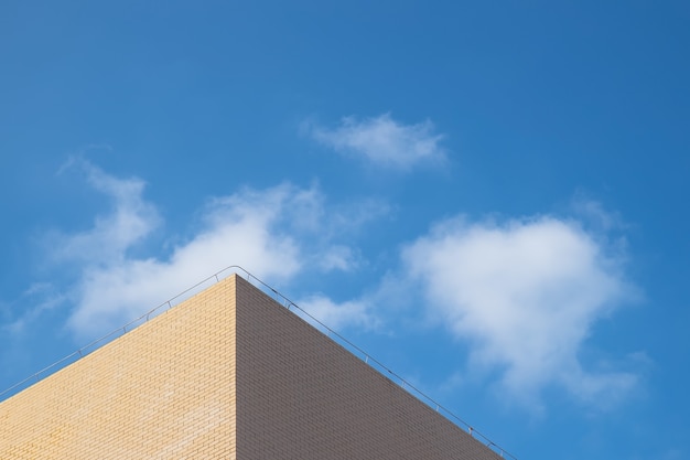 Een deel van het lichtgele gebouw onder de blauwe lucht en witte wolken