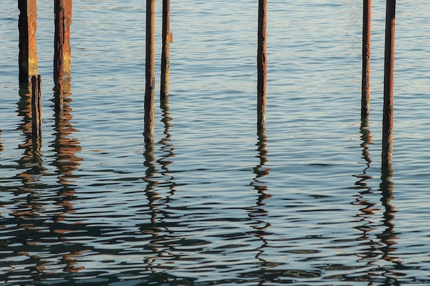 Een deel van houten palen die een pierreflectie in water ondersteunen