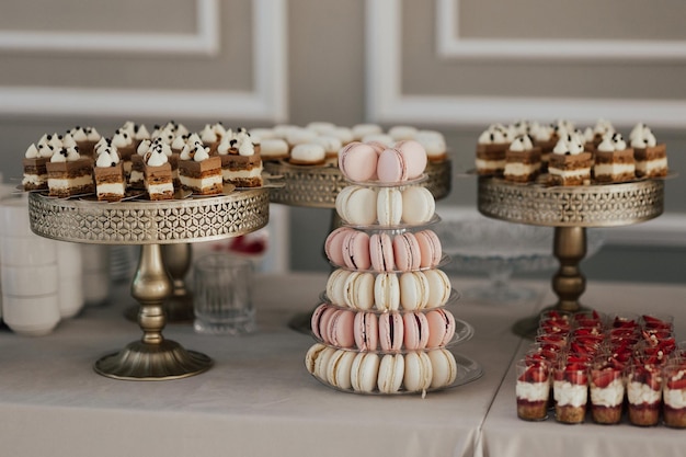 Een desserttafel met een gouden standaard en een witte bitterkoekjes erop.