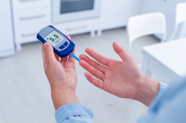 Een diabetespatiënt meet thuis bloedglucose met een glucosemeter. Diabetes hebben en de bloedsuikerspiegel onder controle houden