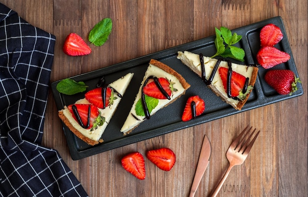 Een dienblad met aardbeiencheesecake met aardbeien erop