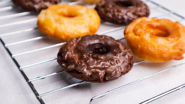 Foto een dienblad met donuts op een rek waarvan er één geglazuurd is.