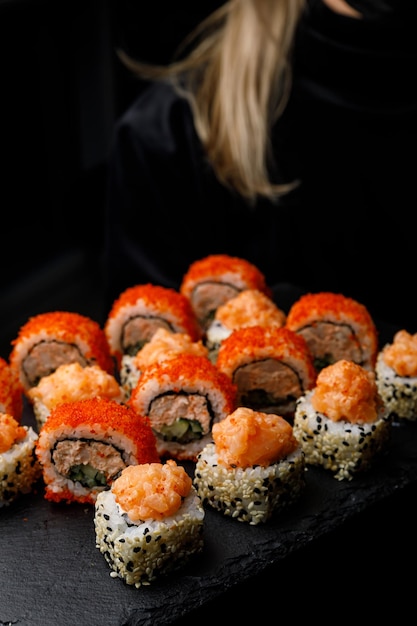 Een dienblad sushi met een vrouw op de achtergrond