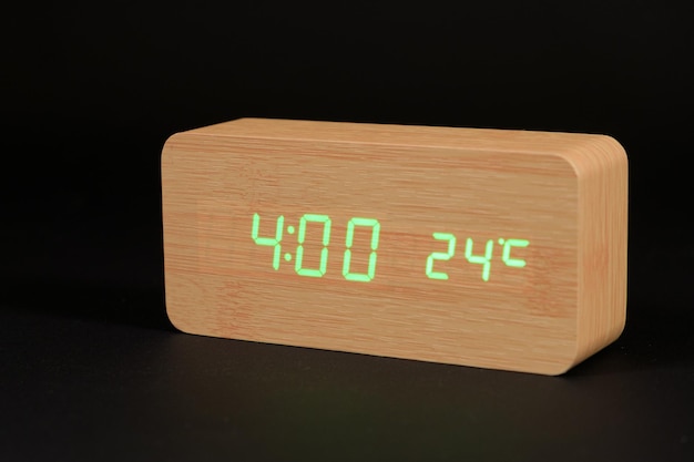 Een digitale houten klok met een thermometer op een zwarte achtergrond