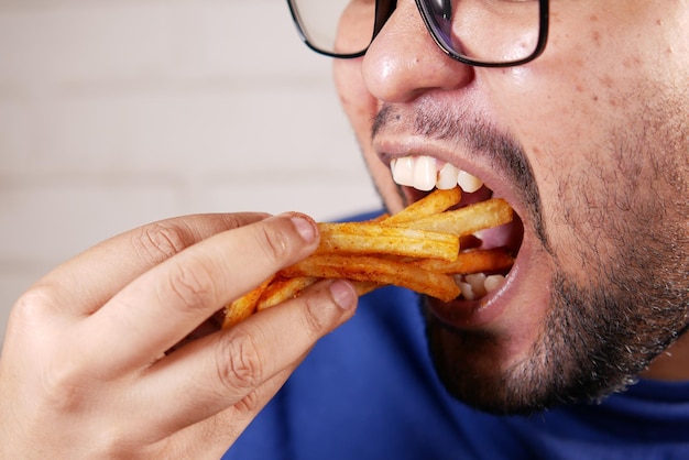 Een dikke man die frietjes eet terwijl hij zit