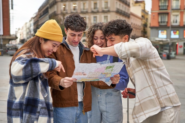 Een diverse groep vrienden die lachen en hun sightseeingavontuur in Madrid plannen met een stadsplattegrond