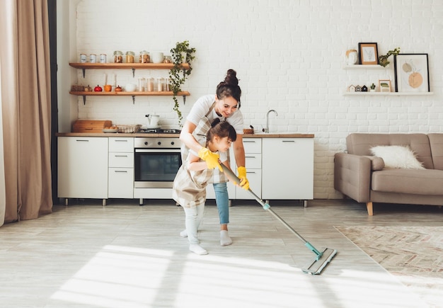 Een dochtertje en haar moeder maken het huis schoon een kind wast de keukenvloer een schattig klein hulpmeisje maakt de vloer schoon met een dweil een gelukkig gezin maakt de kamer schoon