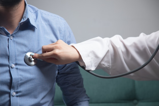 Een dokter controleert het hart van een man met een stethoscoop