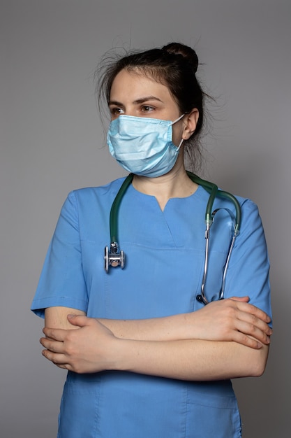 Een dokter in een blauw uniform met een medisch masker kijkt weg