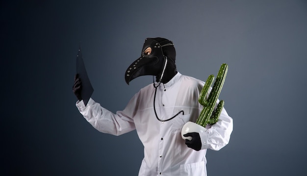 Een dokter in een kamerjas, gekleed in een pestdoktermasker met een cactus in zijn handen