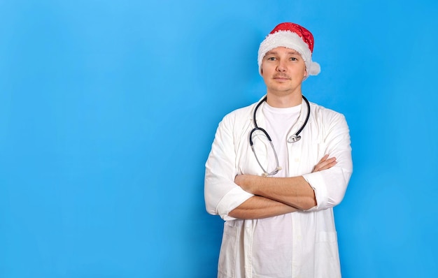 Een dokter met een rode hoed van de Kerstman en een witte jas kijkt in de camera op een blauwe rug