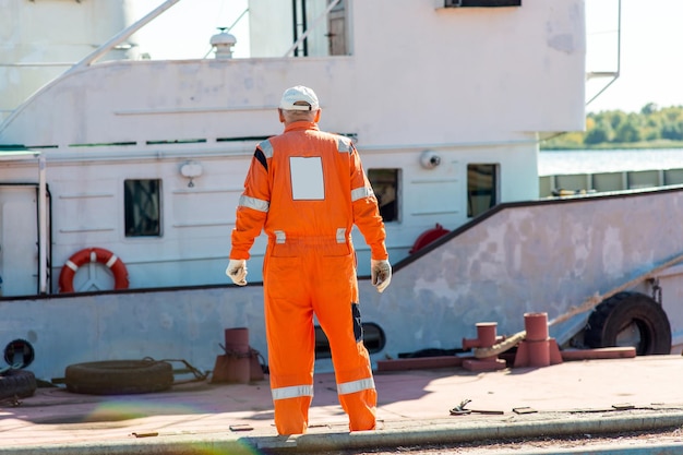 Een dokwerker loopt langs de pier tegen de achtergrond van een meerboot