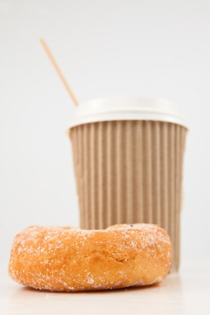 Een donut en een kop koffie naast elkaar geplaatst