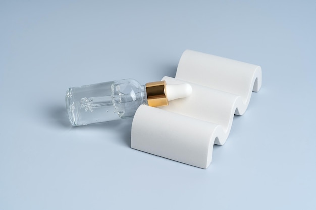 Een doorzichtig serum of gel in een druppelfles op een wit betonnen podium voor de presentatie van het product