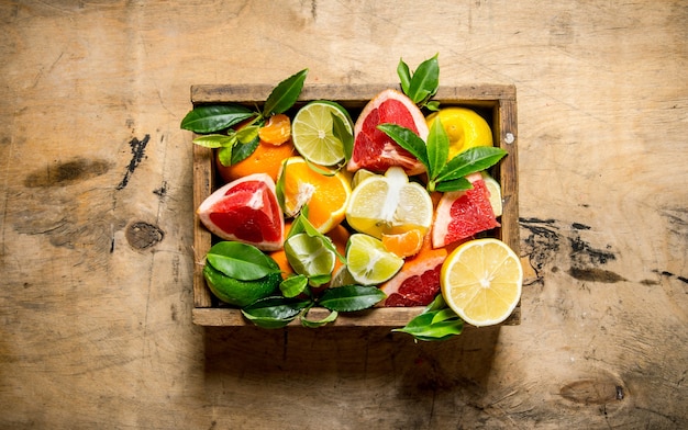 Een doos met citrusvruchten - grapefruit, sinaasappel, mandarijn, citroen, limoen en bladeren