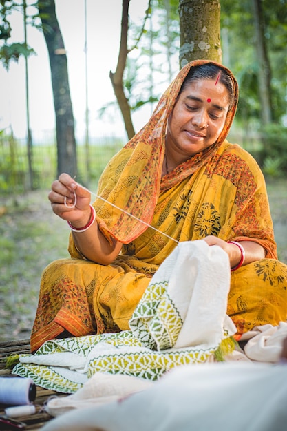 Een dorpsvrouw in het district Rangpur in Bangladesh borduurt met de hand